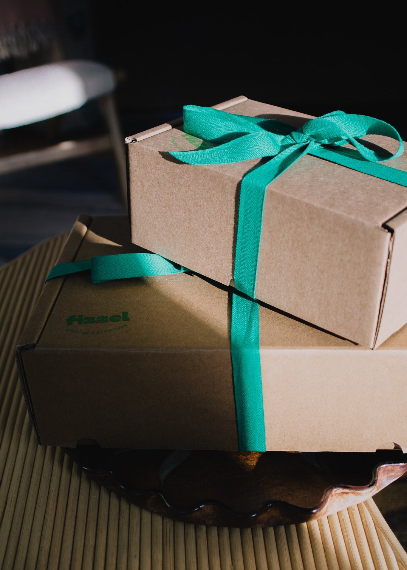 Two cardboard boxes tied with green ribbons on a textured surface.